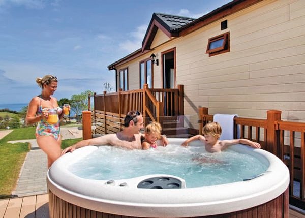 Family enjoying hot tub outside Ladram Bay Holiday Park Lodge