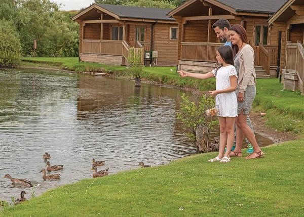 A family feeding ducks in the lake of Dacre Lakeside Park