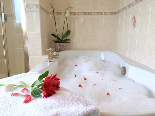 Bathtub with bubble bath foam and a flower