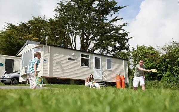 Family playing badminton outside thorpe park's caravan