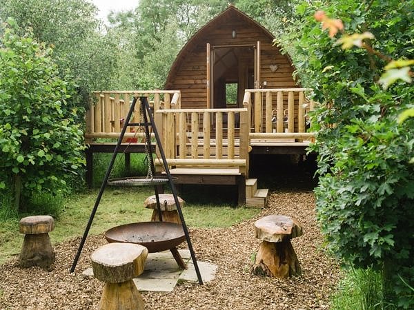 Wooden barrel cabin with veranda and bonfire place outside